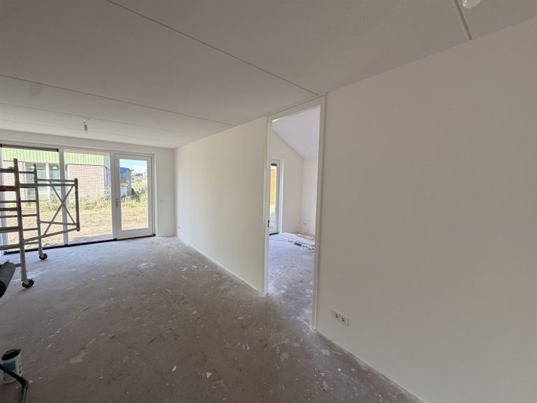 Ruime woonkamer in nieuwbouw met egale wanden van renovlies, klaar voor de vloer